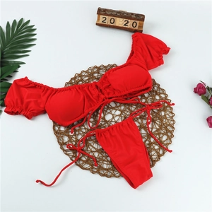 Flachliegender roter Off-Shoulder-Bikini mit Puffärmeln und Schnürung auf Webmatte