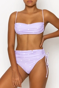 Close-up of light purple polka dot bikini featuring high waist ruching and gold heart charm