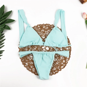 Flat lay of a light blue two-piece bikini set with ruched details on woven mat