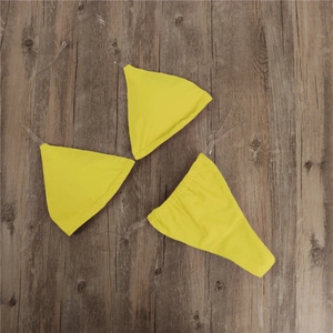 Flat lay of yellow bikini with transparent straps on dark wood background