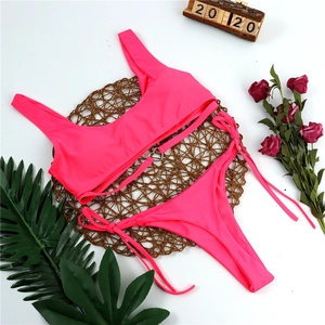Detail of pink bikini with heart metal buckle on woven mat with floral decor