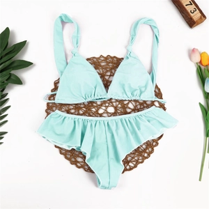 Minzgrünes Bikini-Set mit Rüschenbesatz oben und unten auf einer gewebten Matte mit Deko