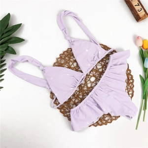 Detailaufnahme von flachgelegtem lila gepunktetem Bikini-Set mit Rüschen und Sommerdeko