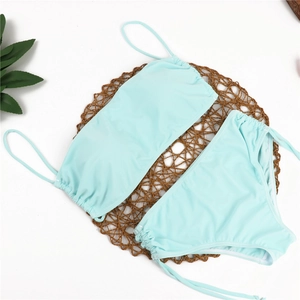 Detailed flat lay of mint green high-waisted bikini set on a brown woven mat