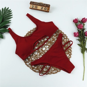 Detail eines gerippten dunkelroten Bikinis mit Cut-Out-Trägern auf einer Strohmatte