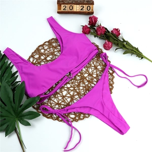 Flat lay of fuchsia bikini set with tie-side bottoms on a round woven straw mat