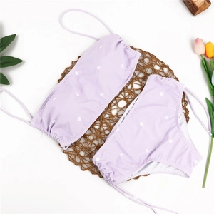 Flat lay of lavender polka dot bikini set with bandeau top and side-tie bottoms