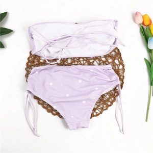 Flat lay of a two-piece lavender polka dot bikini with high waist bottoms and tie sides