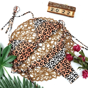 Flat lay of leopard print bikini with halter top and side-tie bottoms on a woven mat
