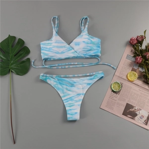 Vue à plat du bikini tie-dye bleu avec bretelles croisées et accessoires de vacances