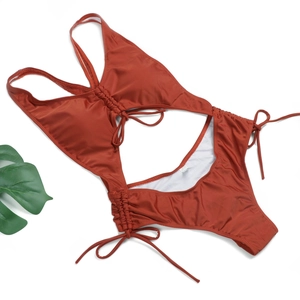 Gros plan sur un maillot de bain rouge rouille avec découpes, cordons et doublure blanche