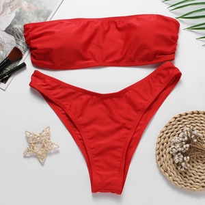 Vue à plat d'un bikini bandeau rouge avec feuilles de palmier et accessoires d'été