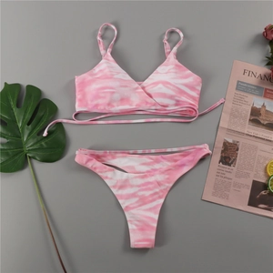 Détail macro d'un ensemble bikini tie-dye rose avec lanières croisées sur une surface plane