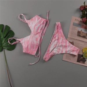 Mise à plat de bikini tie-dye rose et blanc avec bretelles réglables sur fond gris