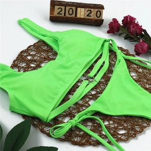 Flat lay of neon green bikini set featuring metal heart rings and tie-side bottoms