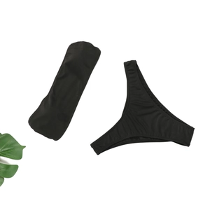 Mise à plat d'un ensemble bikini bandeau noir deux pièces avec bas string sur fond blanc