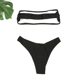 Détail à plat d'un bikini noir deux pièces avec haut bandeau évidé et culotte échancrée sexy