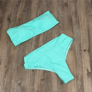 Flat lay of a two-piece mint green high-waisted bikini set on a vintage wooden background