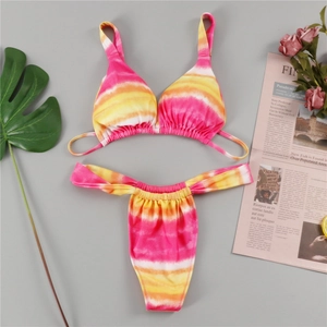 Flat lay of pink tie-dye bikini set with tropical leaves and fashion newspaper details