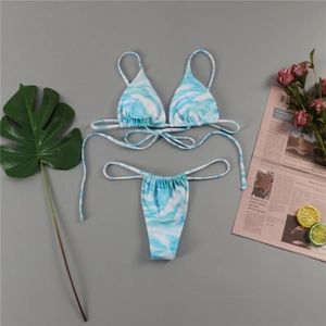 Detailed flat lay of blue and white tie-dye bikini set with summer holiday props