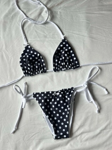 Detailed flat lay of black polka dot bikini top with cute white bow and side-tie bottoms