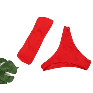 Détail à plat d'un ensemble bikini bandeau rouge vif avec accent de feuille tropicale