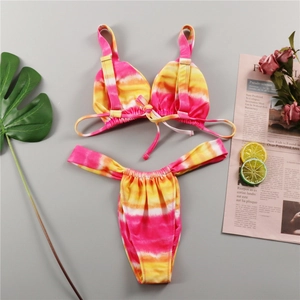 Detailed flat lay of tie-dye bikini set with gold buckles and summer decor elements