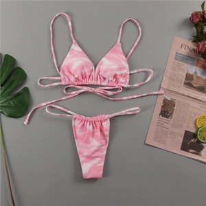 Flat lay of pink and white tie-dye bikini set with string ties and summer props