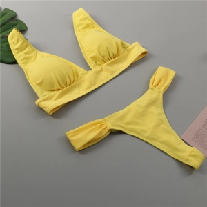 Flat lay view of a bright yellow two-piece bikini set with high-elastic fabric and halter top