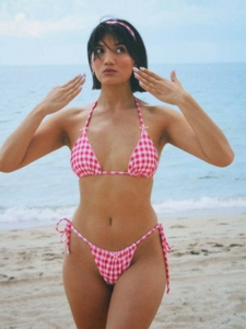 Three-piece red gingham bikini set with bow details and matching headband on beach