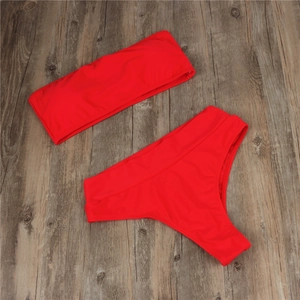 Flat lay view of a solid red two-piece bikini set with high-waist bottoms on wooden floor