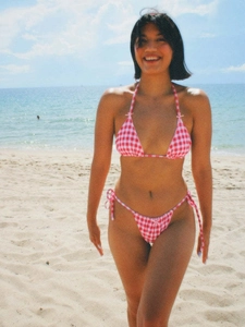 Chic red gingham bow bikini set with tie-side bottoms on a sunny beach setting