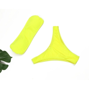 Ensemble bikini bandeau jaune fluo à plat avec des feuilles tropicales sur fond blanc