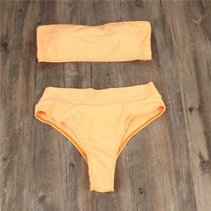 Flat lay view of peach high-waisted bikini with bandeau top on wooden background