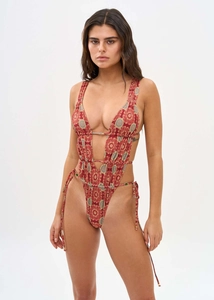 Detail of deep V-neck monokini featuring red mandala print and lace-up cutout design