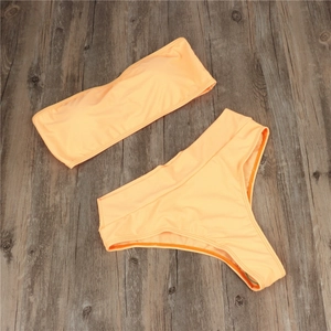 Flat-lay view of peach bandeau bikini set with high-waisted bottoms on dark wood
