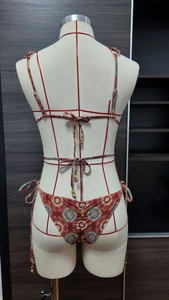 Detail of red floral bikini with criss-cross waist straps and golden bead accents