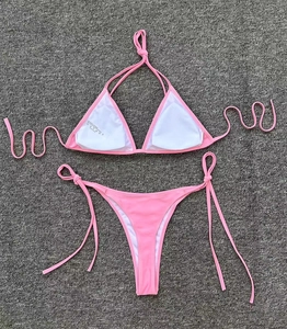 Pink two-piece bikini set with halter top and side-tie bottoms shown on a textured rug