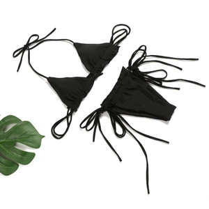 Detailansicht eines schwarzen gerafften String-Bikini-Sets mit Bindebändern auf weiß