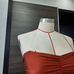 Detail of rust red tube top swimwear featuring pleated chest and clear straps