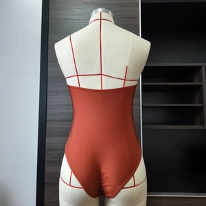 Close-up of metallic copper one-piece swimsuit featuring an open back design on a mannequin