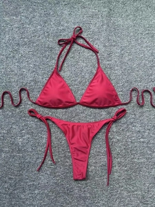 Detailed top view of a dark red triangle bikini set with side tie bottoms on a textured rug