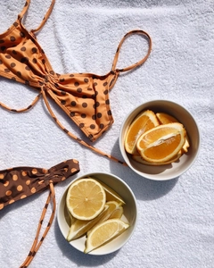 Vue à plat d'un bikini à pois orange rétro avec des agrumes sur une serviette blanche