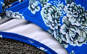 Macro detail of blue floral bikini fabric with white lining and precise double stitching