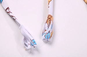 Détail des cordons à imprimé floral sur le tissu blanc d'un bikini en polyester