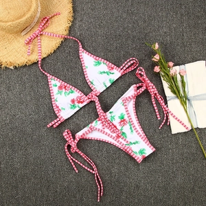 Detailed flat lay of a floral bikini set with red gingham ties and rose pattern print