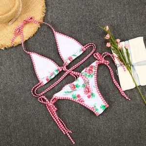 Detailed flat lay of floral bikini set with red gingham ties on dark sand background