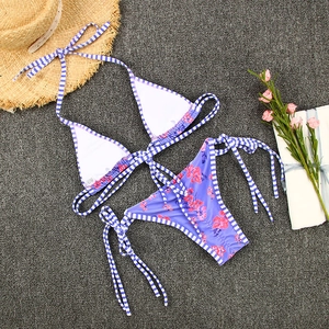 Flat lay of purple floral string bikini set with sun hat for summer beach vacation