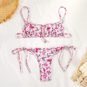 Detailed flat lay of a pink floral bikini set with rose prints and side-tie bottoms