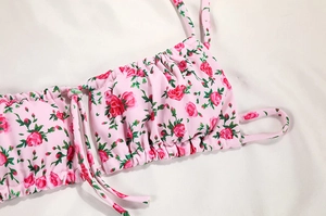 Detailed view of floral bikini top with rose print, ruching, and adjustable drawstring